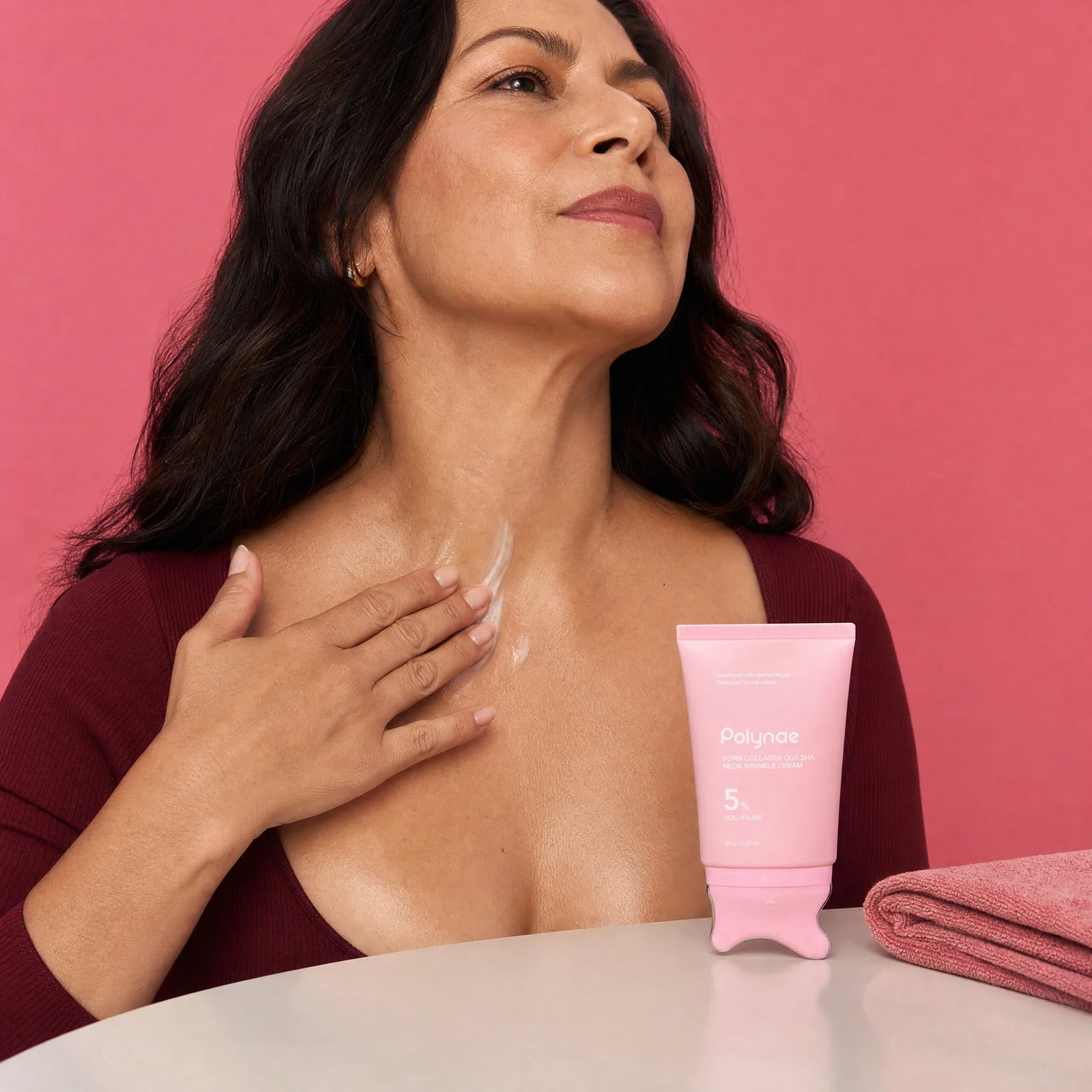 Close-up of woman smoothing Polynae neck cream along her décolletage, cream visibly spread across skin