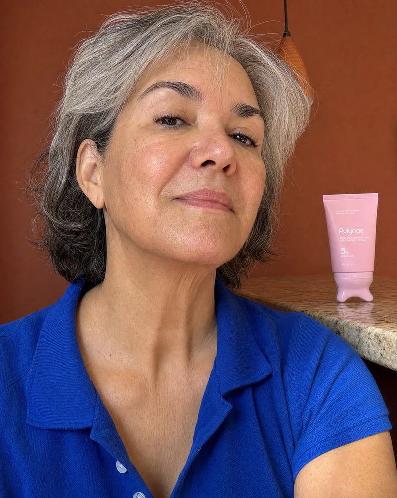 Silver-haired woman in blue polo with Polynae neck cream tube on table beside her, neck skin visible