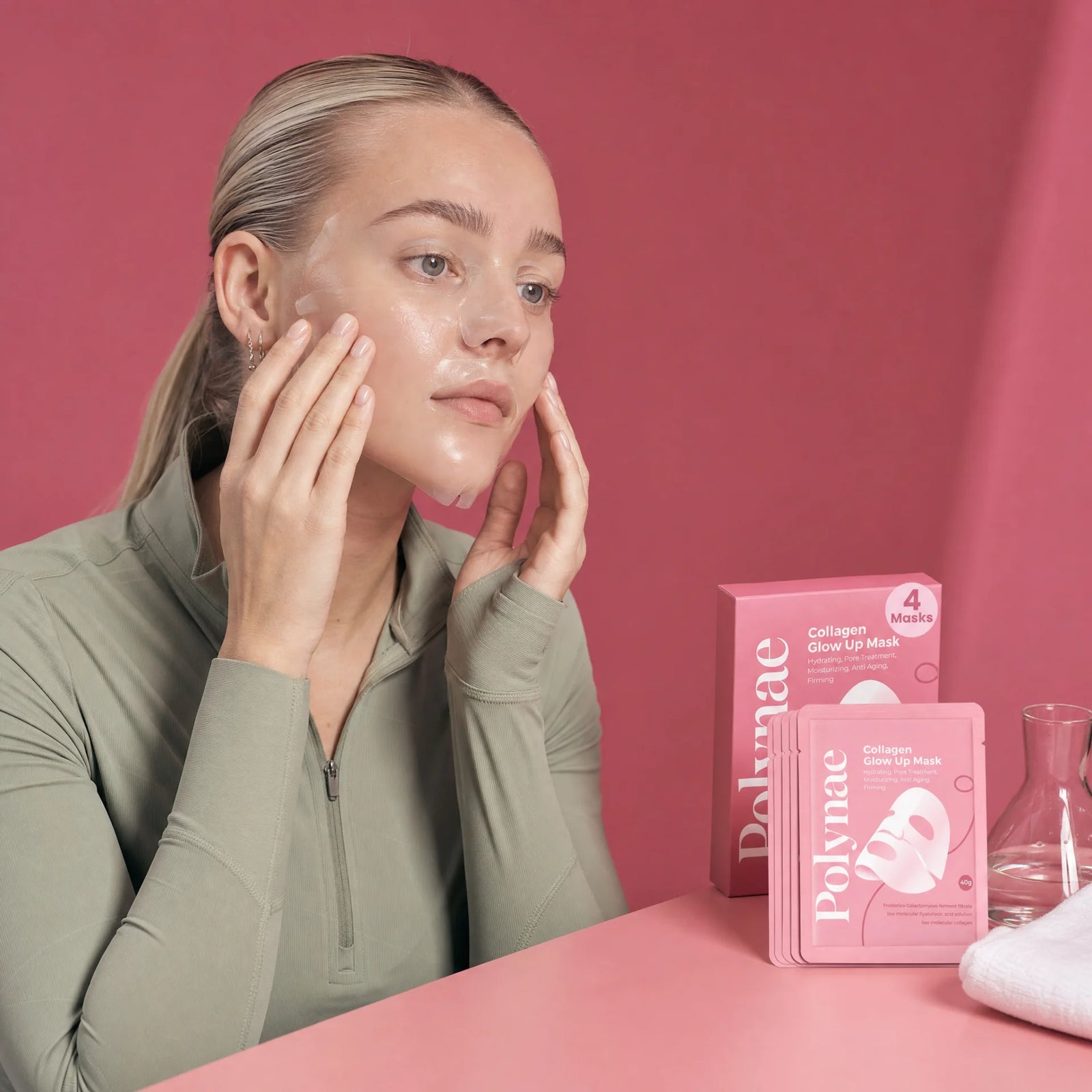 Close-up of a woman pressing the Polynae sheet mask serum into her cheeks with both hands, Polynae box visible beside her