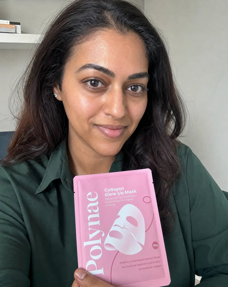 Woman in a green shirt holding a Polynae Collagen Glow Up Mask packet toward the camera, skin visibly smooth and luminous